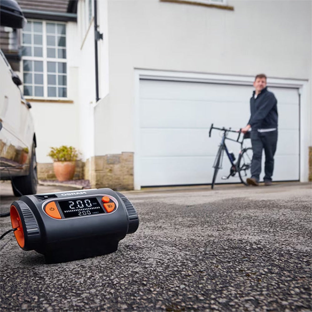 Osram TYREinflate 2130 kompressor på indkørsel med mand og cykel i baggrunden
