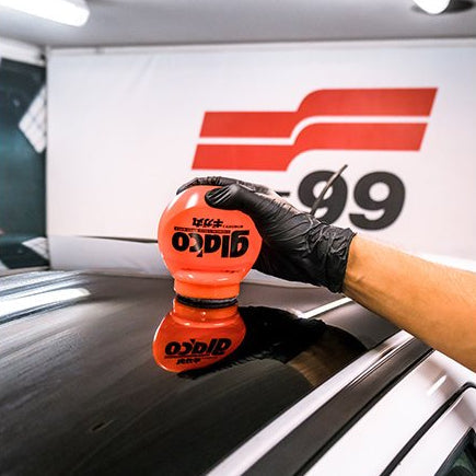 Hand med Glaco Roll-on Max rullbeläggning på bilruta för ultra hydrofobisk effekt