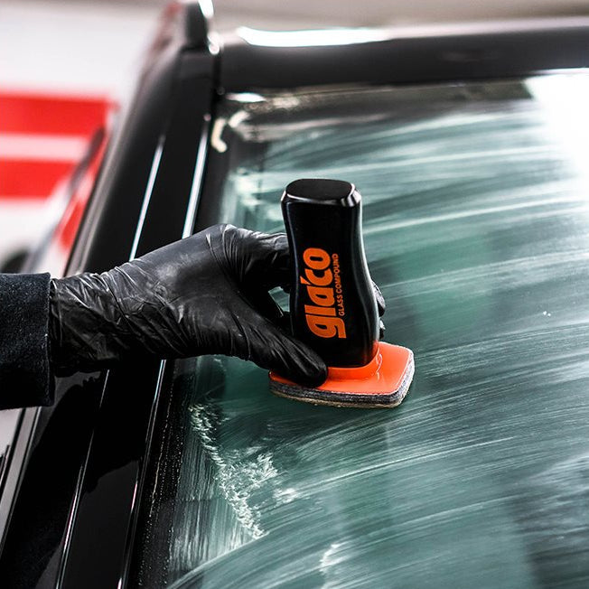 En hand med svart handske applicerar Glaco Glass Compound på bilruta.