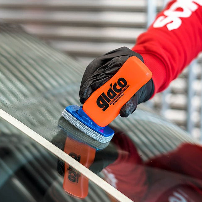 Hand med Glaco DX glasförsegling på bilruta nära vit tejp