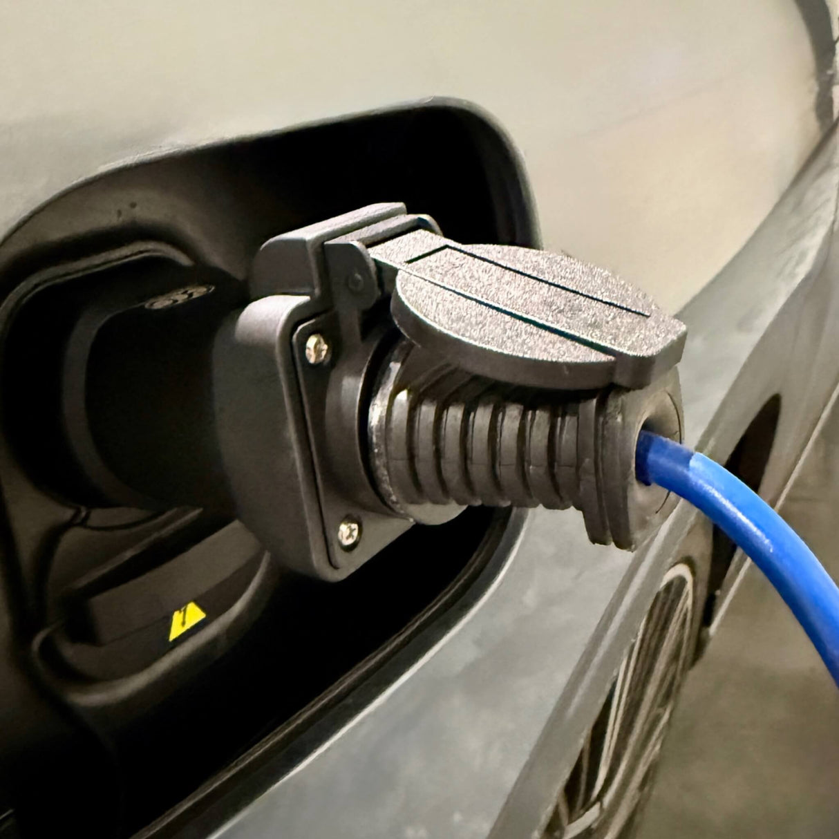 Hand som sätter i eller tar bort GCG Max V2L-adapter i bilens laddningsport