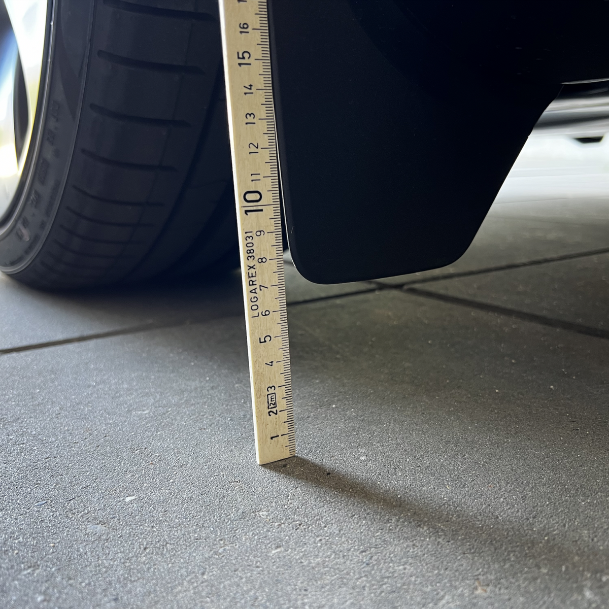 Originala stänkskydd på Tesla Model Y mätta med linjal.
