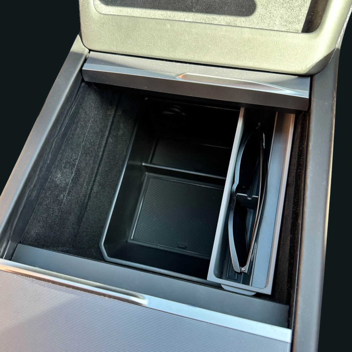Solglasögonhållare installerad i mittkonsolen på en Tesla med solglasögon placerade i hållaren.