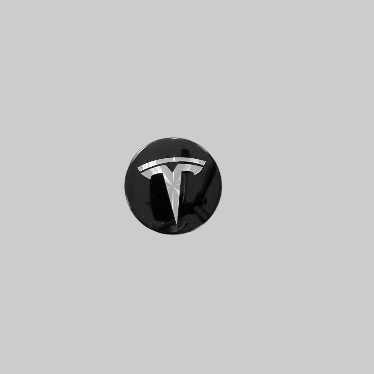 blank svart navkapsel med silver Tesla-logotyp