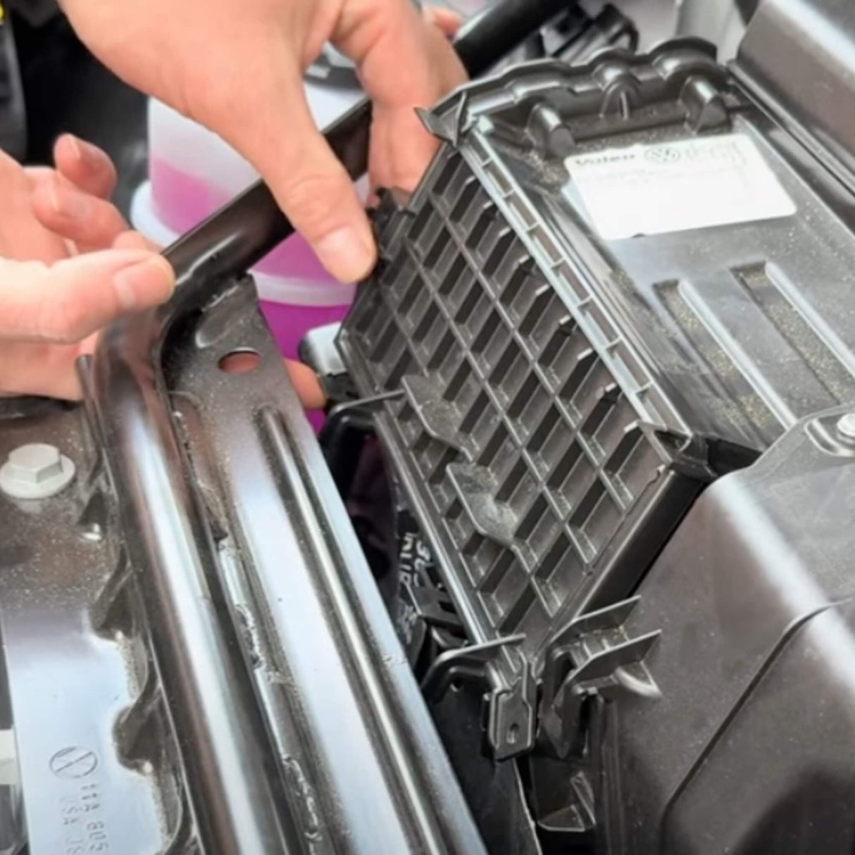 Person installerar ett kolfilter i motorutrymmet på en VW ID.3/4/5/6/7.