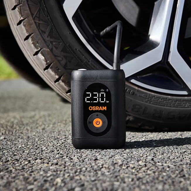 Osram TYREinflate 1600 står på grus foran bildæk, display viser 230 kPa