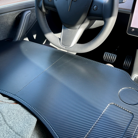 Hopfällbart bord i mörkt kolfiberutseende, sett inne i en Tesla-bil