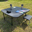 svart campingbord med kaffekopp, barnböcker och en surfplatta