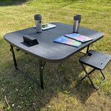svart campingbord med kaffekopp, barnböcker och en surfplatta