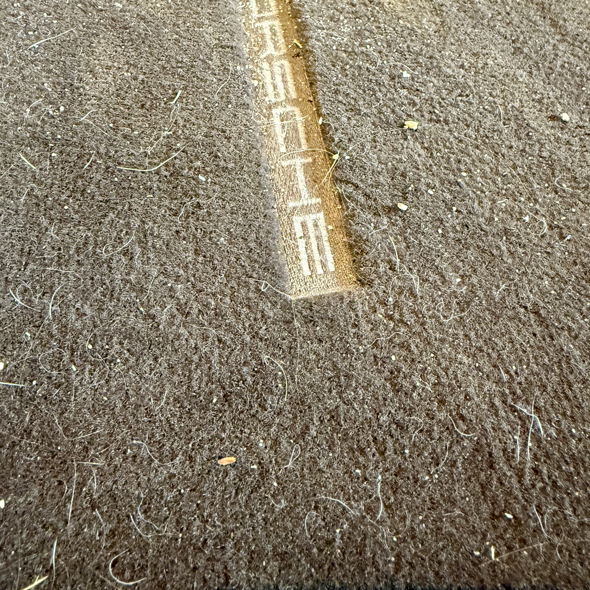 Före-bild av smutsig bilmatta med Porsche-logotyp före TurboClean dammsugare