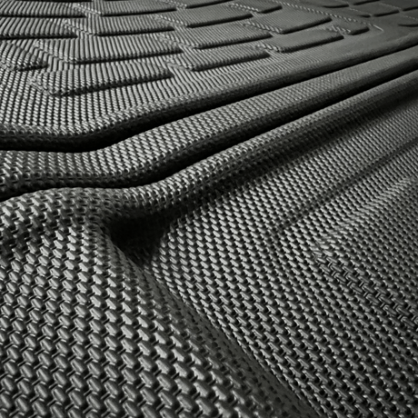 Närbild av en svart bilmatta med texturerade räfflor.