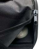 Svart väska med öppen dragkedja och en reflekterande kula inuti