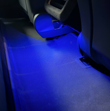Blått LED-ljus lyser ner på en matta bakom sätena.
