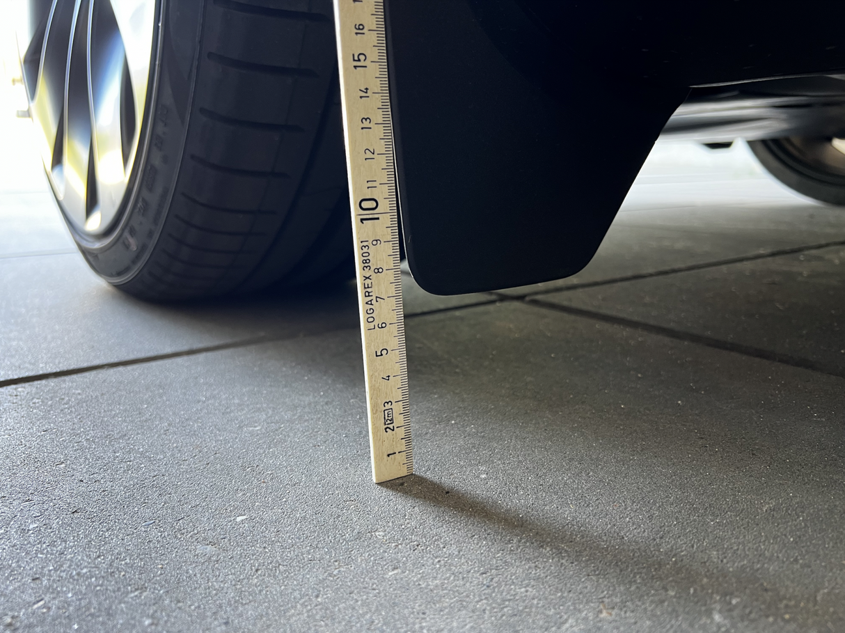 Originala stänkskydd på Tesla Model Y mätta med linjal.