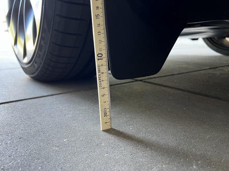 Originala stänkskydd på Tesla Model Y mätta med linjal.
