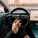 Hand håller S3XY Stalks blinkersarm framför Tesla Model 3 Highland ratt.