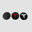 Tre Tesla navkapslar i svart, rött och vitt för fälgar.