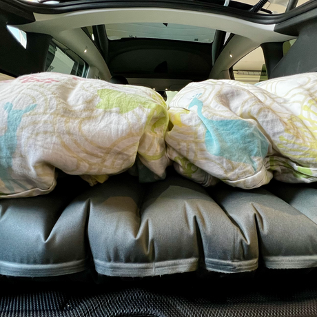 Luftmadrass med sängkläder i bagageutrymmet på en Tesla Model Y för bilsemester.