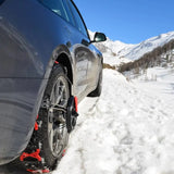 Snökedjor monterade på ett grått bildäck i snötäckta berg